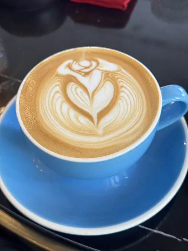 A latte with a rosetta drawn in the foam in a blue cup