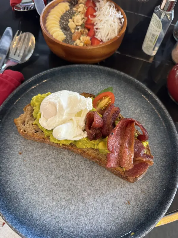 Toast topped with avocado, a poached egg and bacon